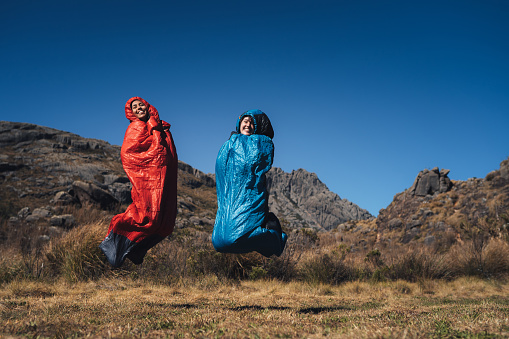 Women jumping on sleeping bag on the mountains