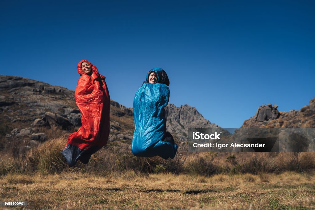 Women jumping on sleeping bag Women jumping on sleeping bag on the mountains Humor Stock Photo