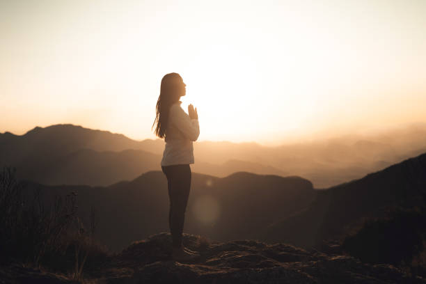 istock Woman meditating at sunset in the mountains 1455601128