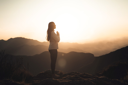 Woman meditating at sunset in the mountains
