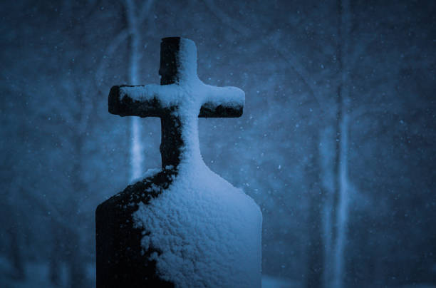 A close up of snow covered cross at a graveyard