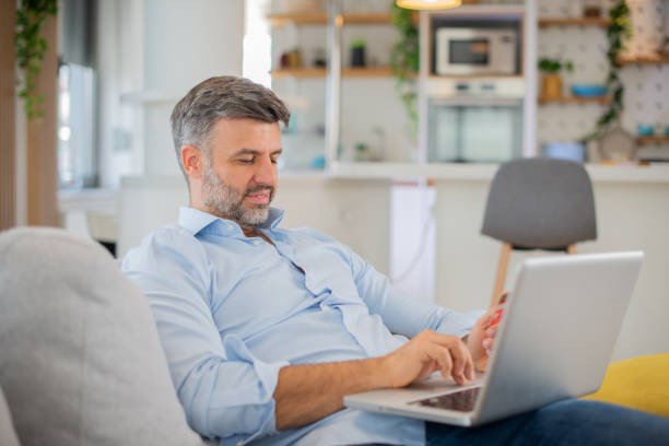 istock Cheerful man doing online shopping 1455604987