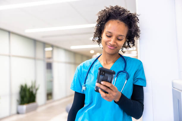 Portrait of a young female nurse in the hospital hallway using her smartphone stock photo