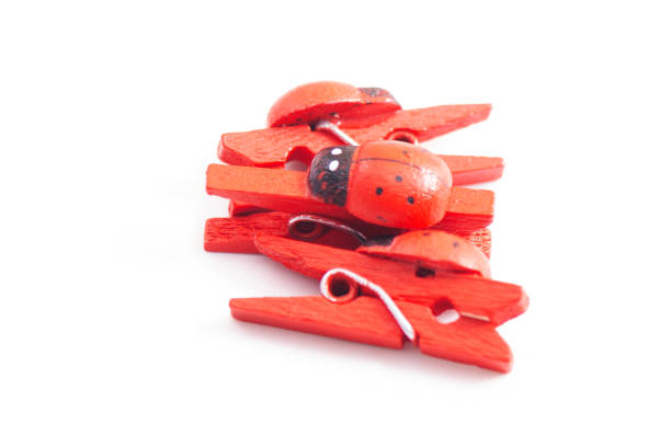 A close up, shot of purple clothes pegs standing on a white background. The focus is on one of the pegs is lying flat.