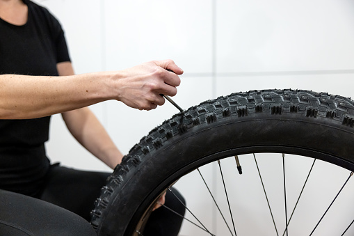 Woman Installing Studs In New Large Fatbike Tires in preparation for winter.