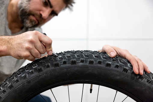 Man Installing Studs In New Large Fatbike Tires in preparation for winter.