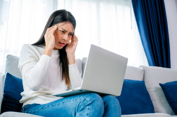 istock Office syndrome. Overworked tired young asian woman feeling headache, having eyesight problem after computer laptop work. Stressed young woman suffering from fatigue at home 1455620557