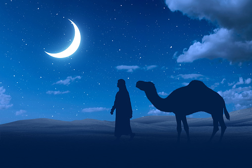 Silhouette of a man and camel crossing the desert with a night scene background