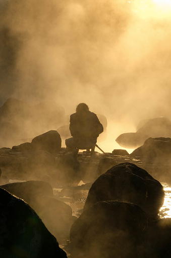 January 8, 2023; Hot springs and fog in Thailand with morning sunlight. Morning atmosphere at Chae Son National Park, silhouette of tourists enjoying the beauty of natural hot spring in Lampang, Thail