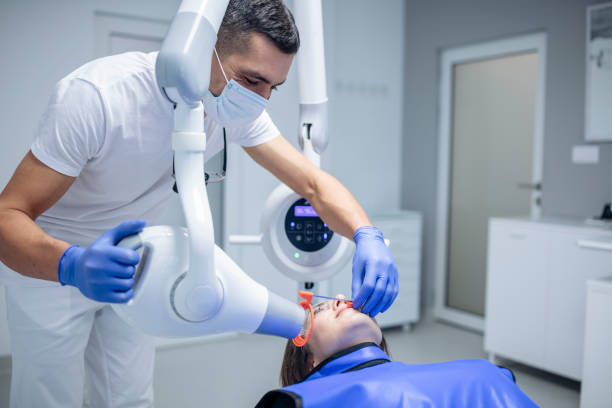 Dentist taking X-rays of patient. A dentist operates an x-ray machine while patient sits with x-ray film in mouth. x ray equipment stock pictures, royalty-free photos & images