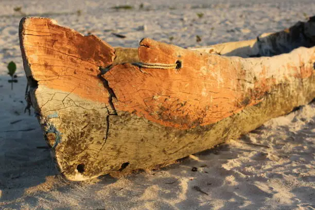 an old copper / orange color wood boat on a white sand beach