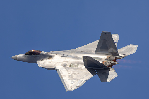 Close side view of a F-22 Raptor in beautiful light ,  with afterburners on