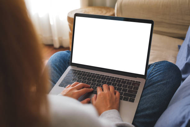 istock Mockup image of a woman working and typing on laptop computer with blank screen on sofa at home 1455633410