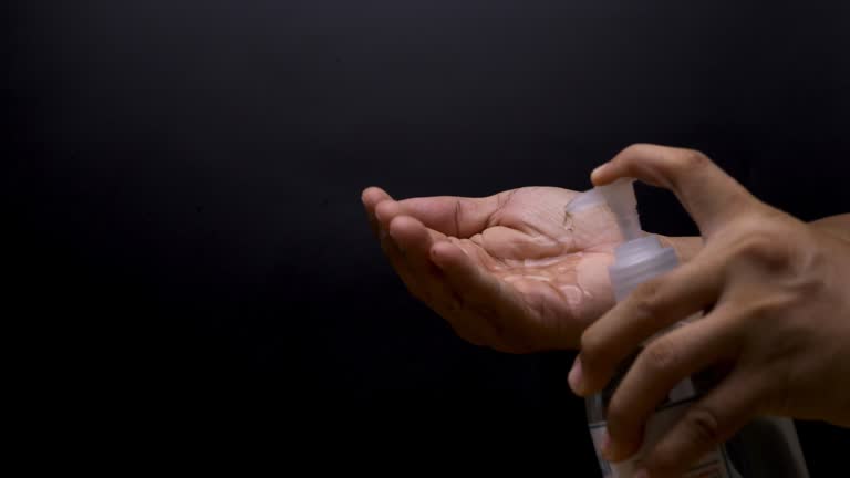 Cleaning hands with antiseptic gel on black background.