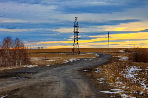 Power poles and a dirt road in a field in late autumn