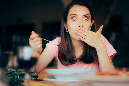 Mujer enferma comiendo sopa en un restaurante sintiendo náuseas photo