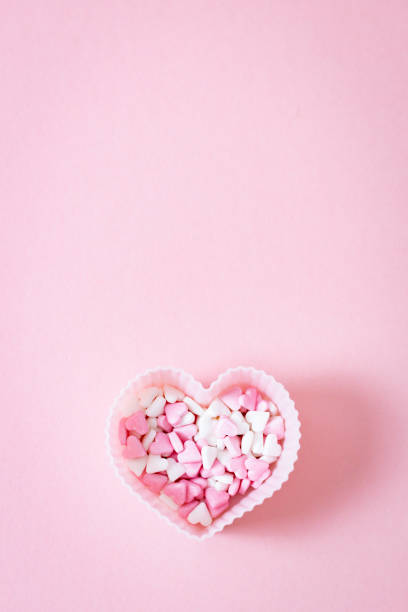 istock One form for a muffin heart with candy sprinkles on a pink background. 1455642860