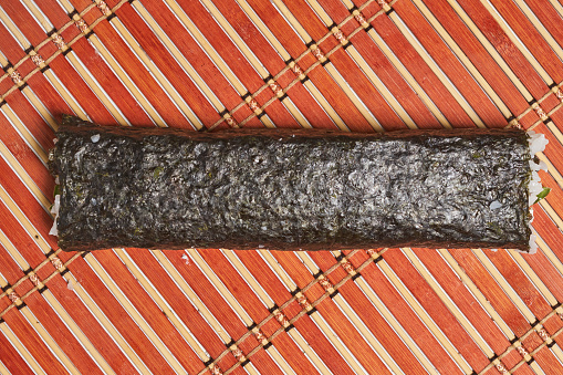 A top view of ready sushi roll on the bamboo rolling mat ready for serving
