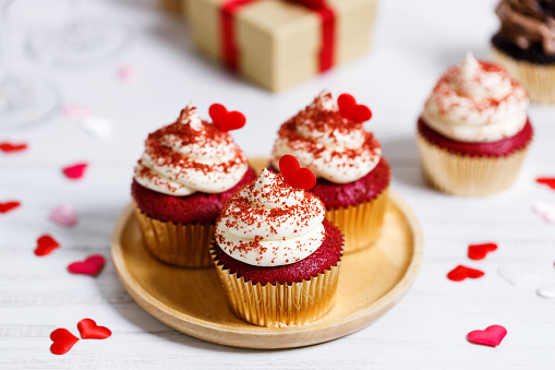 Small cupcakes with red hearts on wooden background. Valentineâs day and sweet pastries concept.