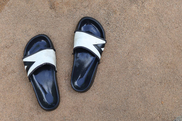 wet black old flip flops on the sand ground, no people with copy space
