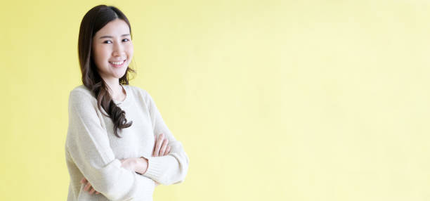 istock Happy asian woman smiling and looking at camera while standing over isolated yellow background, Portrait of asia female with copy space 1455654489