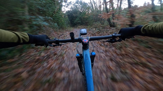 Riding a mountain bike fast through an autumn landscape trail from a rider point of view