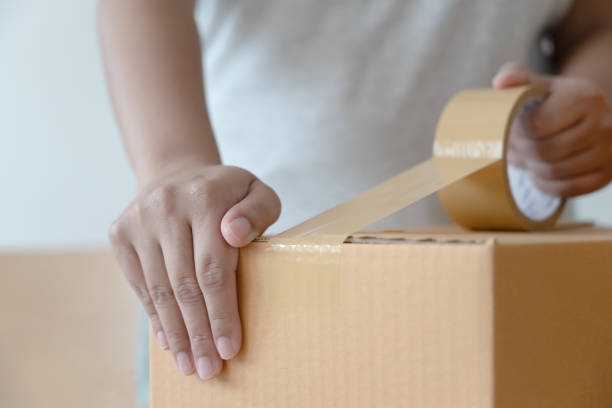 istock Woman sealing tape cardboard box preparing to delivery 1455657113
