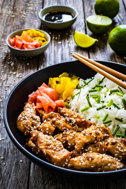 istock Stir-fried chicken meat, white rice and vegetables on wooden table 1455657149