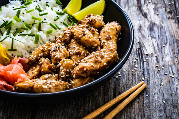 istock Stir-fried chicken meat, white rice and vegetables on wooden table 1455657162