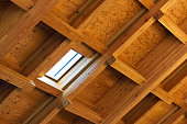 Interior view of a wooden roof structure with beams with skylight