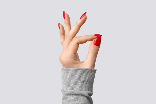 Closeup of hand of a young woman with red manicure on nails against white background