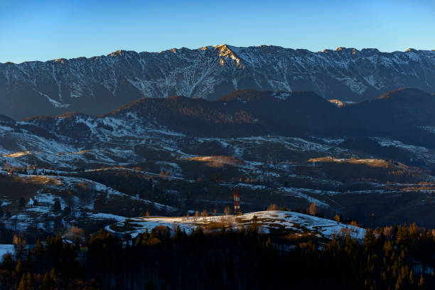 Panoramic winter view of Piatra Craiului National Park, mountain range in the Southern Carpathians, Romania, small villages scattered on the slopes and hills, snowy mountains in the background Panoramic winter view of Piatra Craiului National Park, mountain range in the Southern Carpathians, Romania, small villages scattered on the slopes and hills, snowy mountains in the background zarnesti stock pictures, royalty-free photos & images