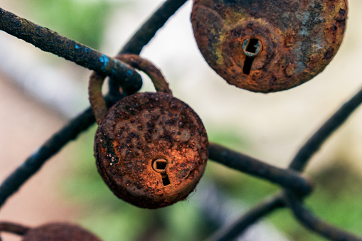 Old rusted padlock attached to grid fence.