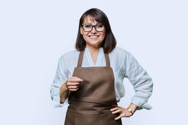 istock Confident middle aged woman in apron looking at camera on white background 1455664688