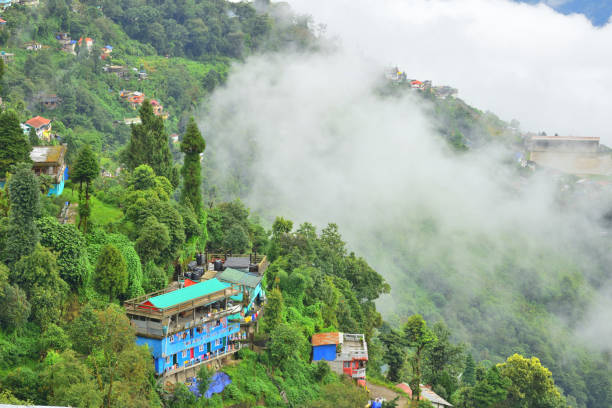 istock Dense clouds over a mountain slope with several houses surrounded by trees. 1455666841