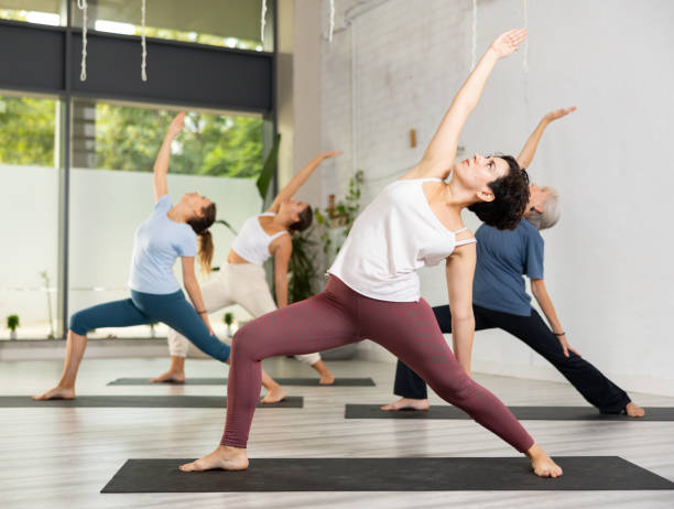 istock Group of young active different ages women doing stretching exercises during yoga class 1455668233