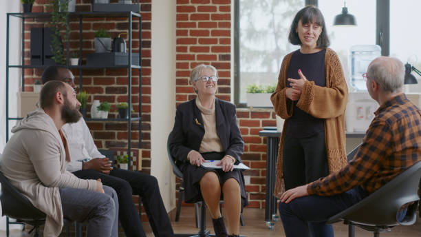 istock Woman sharing therapy progress with group at a meeting and receiving applause 1455669624