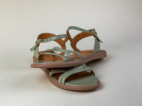Female summer sandals are light gray in color. Pair of female beautiful light summer sandals. Modern summer female shoes for walking outside the home.