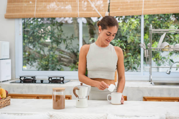 Smiling woman adding protein powder in a coffee
