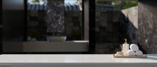 istock Empty space on white tabletop with bath accessories over blurred modern outdoor bathroom. 1455672933