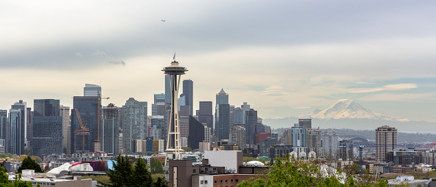 A scenic cityscape of the Seattle with a snowy mountain and dark clouds in the background