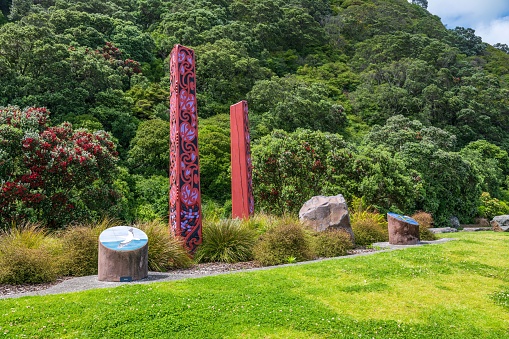 Whakatane, New Zealand – November 19, 2022: A scenic view of tribal Maori carvings in the Whakatane park surrounded by evergreen hills