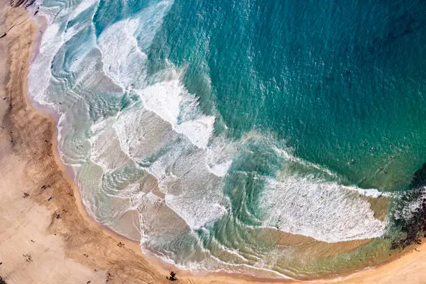 An aerial view of the wavy sea hitting the sandy