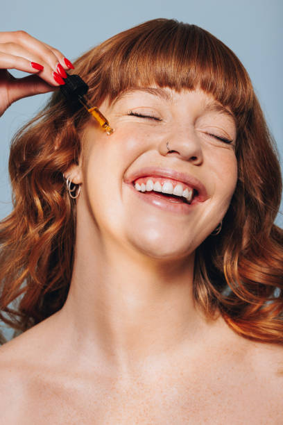 istock Smiling woman applying face serum with a dropper in a studio 1455676418