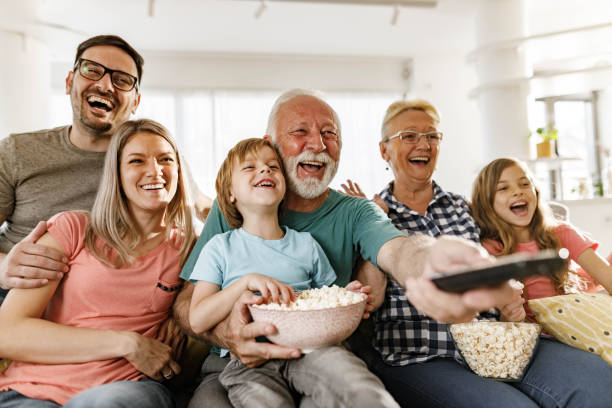 família alegre se divertindo enquanto assistia a um filme em casa. - changing channels - fotografias e filmes do acervo