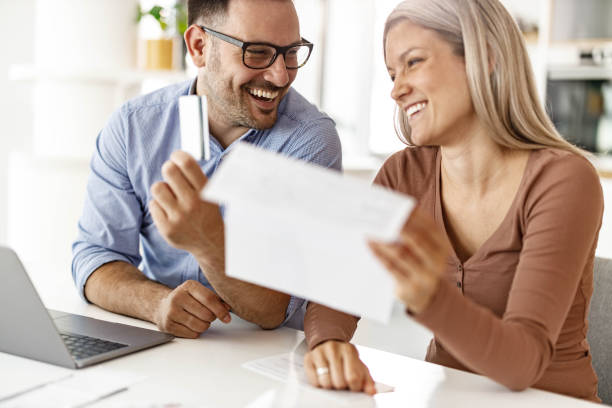 istock Happy couple talking while paying their bills over laptop at home. 1455677568