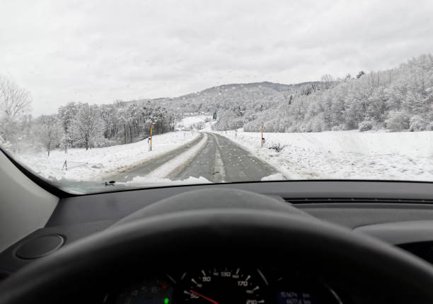 istock View from the car on a snowy road with trees 1455678873