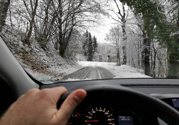 istock View from the car on a snowy road with trees 1455678877