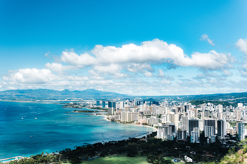 A sweeping view of Honolulu, Hawaii, USA, on the coast of the Pacific ocean under a bright cloudy sky