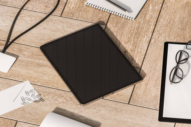 istock Perspective view on modern digital tablet with blank dark screen and space for your logo or text on wooden parquet surface among office tools. 3D rendering, mock up 1455679565